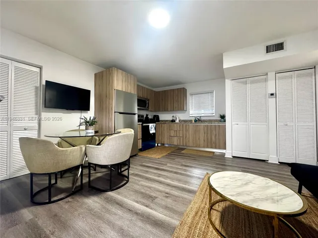 a living room with furniture a flat screen tv and kitchen view