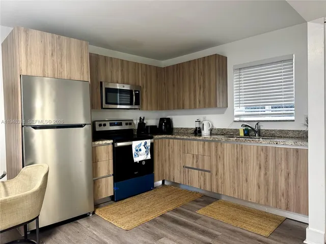 a kitchen with granite countertop a refrigerator stove top oven and sink