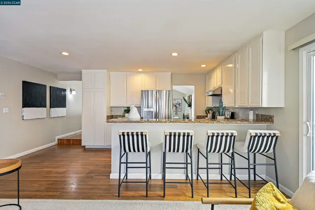 a kitchen with stainless steel appliances granite countertop white cabinets a sink and a stove