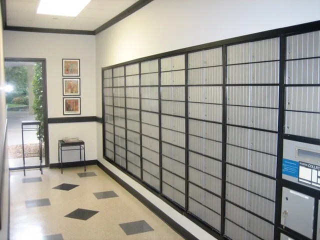 a tall yellow building with trees and couple of cars parked in front of it