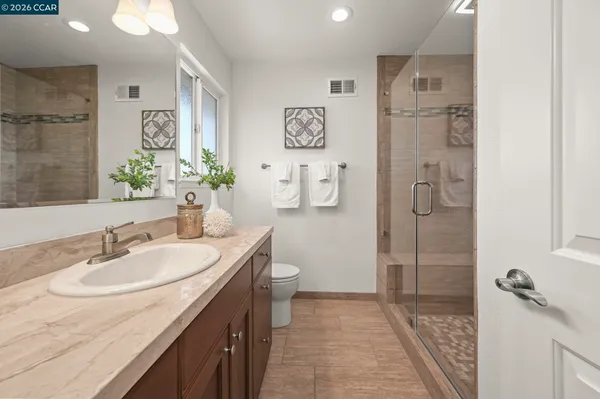 a bathroom with a granite countertop sink a toilet a shower and a mirror