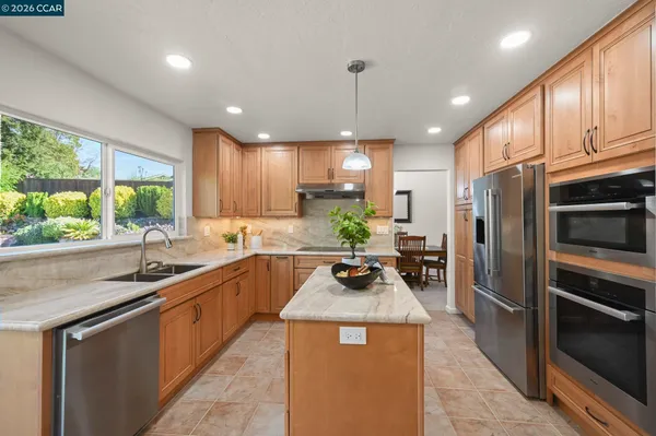 a kitchen with kitchen island granite countertop a sink stainless steel appliances and cabinets