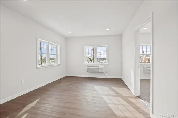 a view of an empty room with a window and wooden floor