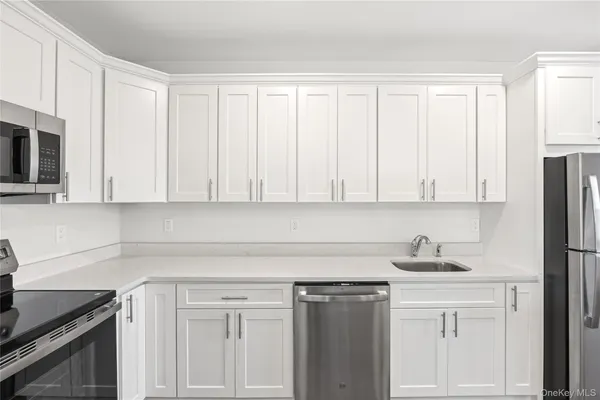 a kitchen with white cabinets and sink