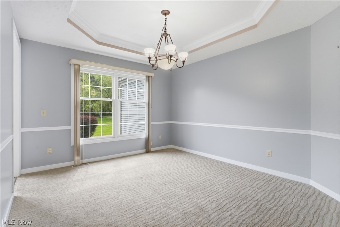 11678 Dunham Road Northfield, OH 44067 - Photo 12 of 38 Recessed ceiling with crown molding, chandelier, chair rail molding, and large window overlooking exterior greenery