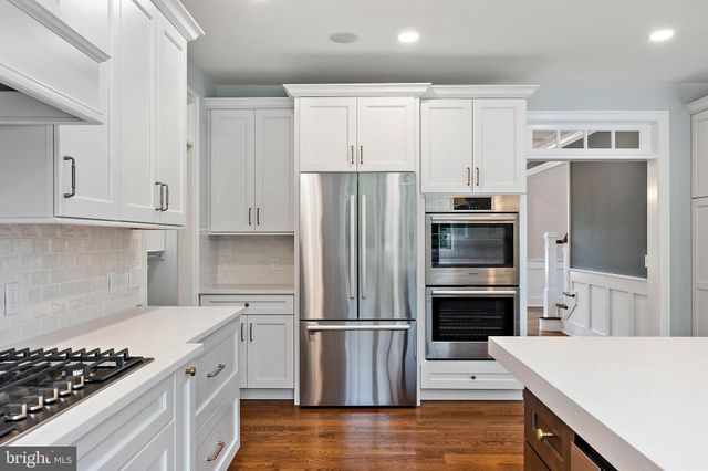 a view of an empty room with wooden floor and a chandelier