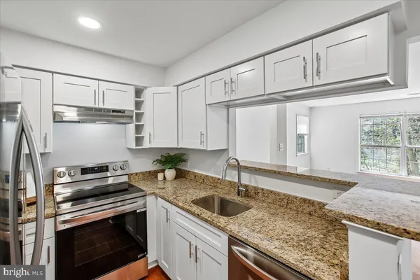 a kitchen with granite countertop a sink a stove and cabinets