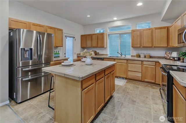 a kitchen with stainless steel appliances granite countertop a sink stove refrigerator and cabinets