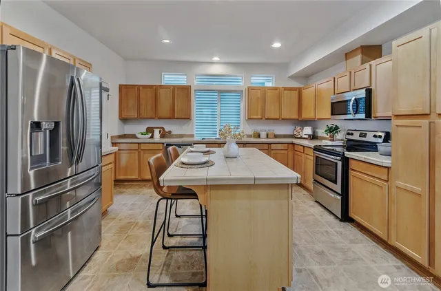 a kitchen with stainless steel appliances granite countertop a refrigerator a sink a stove a microwave and island