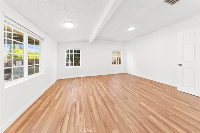 a view of an empty room with wooden floor and windows