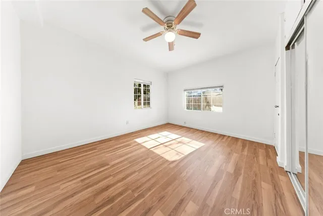 a view of empty room with wooden floor and fan