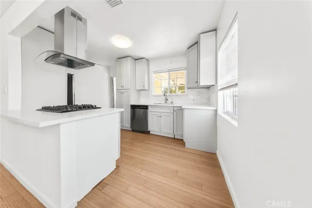 a kitchen with stainless steel appliances granite countertop a sink a stove a refrigerator a island with wooden floor