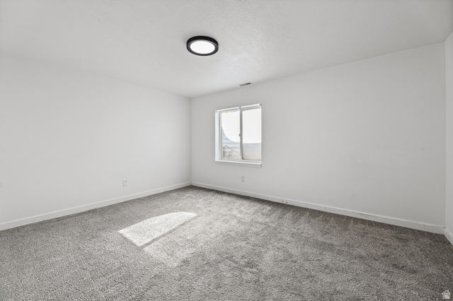 5525 Hampton Way Stansbury Park, UT 84074 - Photo 27 of 35 Spacious room featuring neutral carpeting, white walls, and a modern ceiling light fixture