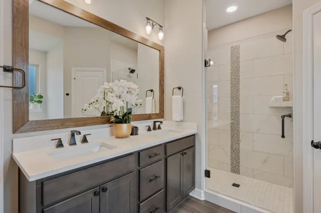 a bathroom with a sink double vanity granite shower and a mirror