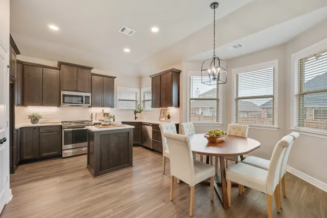 a kitchen with stainless steel appliances granite countertop a stove a sink a dining table and chairs
