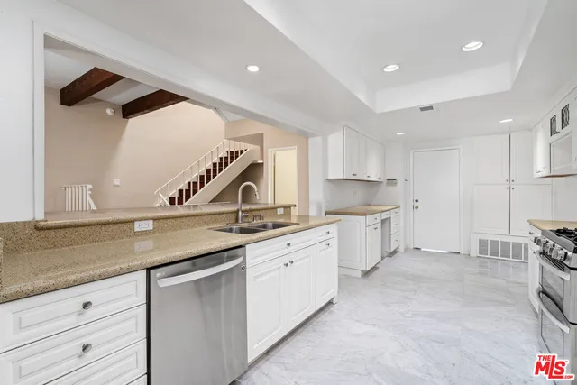 a kitchen with granite countertop a sink and white cabinets