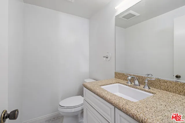 a bathroom with a granite countertop sink a toilet and a mirror