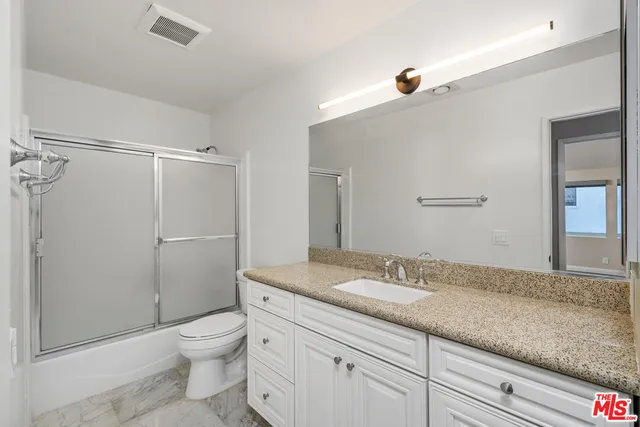a bathroom with a granite countertop sink a toilet and shower