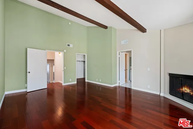 a view of an empty room with wooden floor and a fireplace