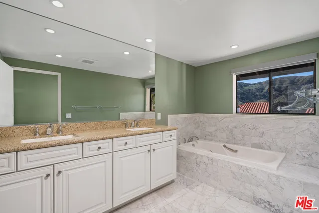 a bathroom with a granite countertop sink mirror and bathtub