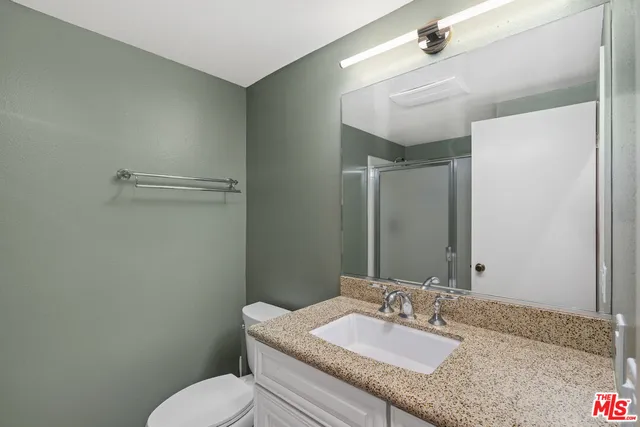 a bathroom with a granite countertop sink mirror vanity and toilet