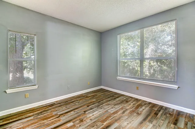 a view of an empty room with wooden floor and a window