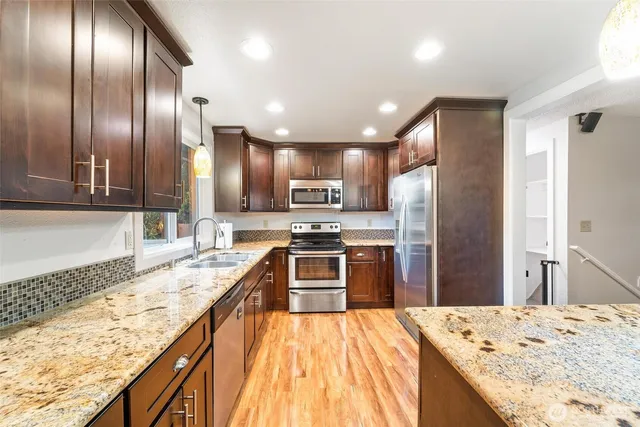 a modern kitchen with granite countertop stainless steel appliances and a refrigerator stove top oven