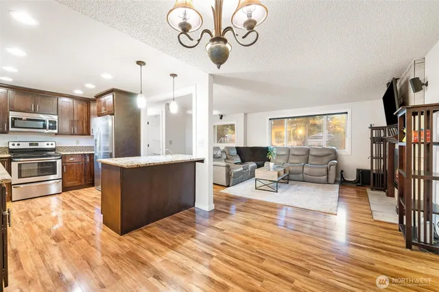 a large white kitchen with a refrigerator a stove a sink dishwasher and a fireplace with wooden floor