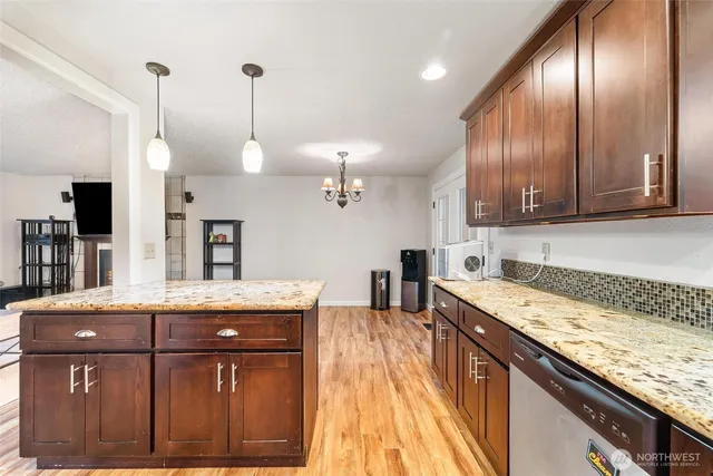 a kitchen with stainless steel appliances granite countertop wooden cabinets a stove top oven a sink and dishwasher