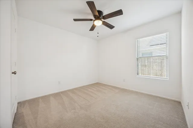 an empty room with a window and a fan