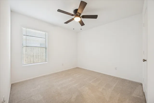an empty room with a window and a fan