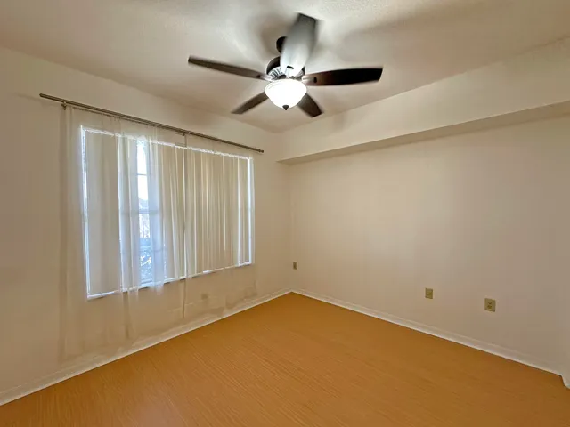a view of an empty room with chandelier fan and a window
