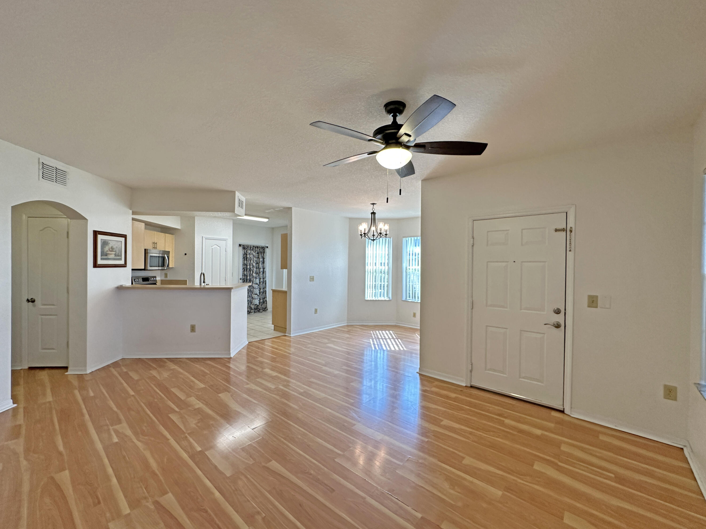 166 Southwest Peacock Boulevard, Unit 104 Port St. Lucie, FL 34986 - Photo 7 of 45 a view of a kitchen with wooden floor and a ceiling fan