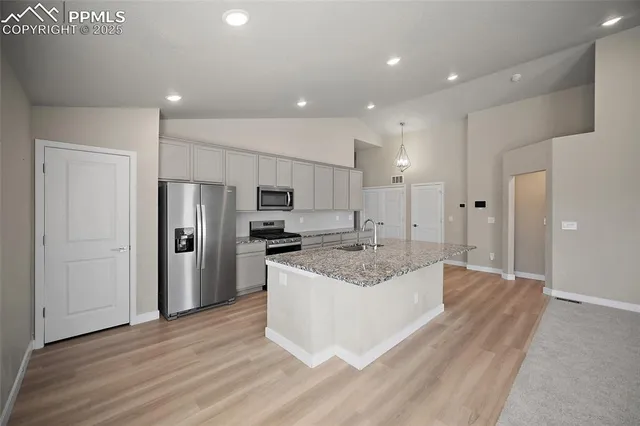 a large kitchen with stainless steel appliances granite countertop a lot of counter space and wooden floor