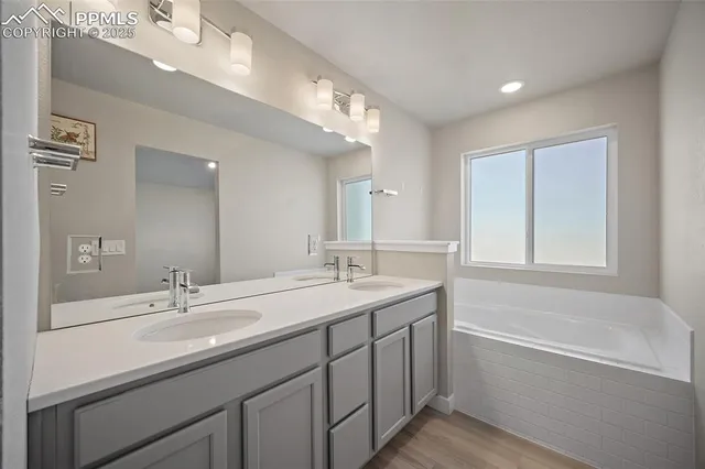 a bathroom with a sink double vanity granite tub and a mirror