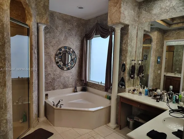 a bathroom with a tub a sink and a large mirror