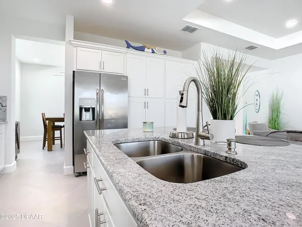 a kitchen with stainless steel appliances kitchen island granite countertop a refrigerator and a sink
