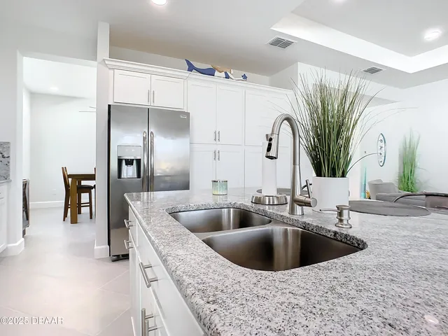 a kitchen with stainless steel appliances kitchen island granite countertop a refrigerator and a sink