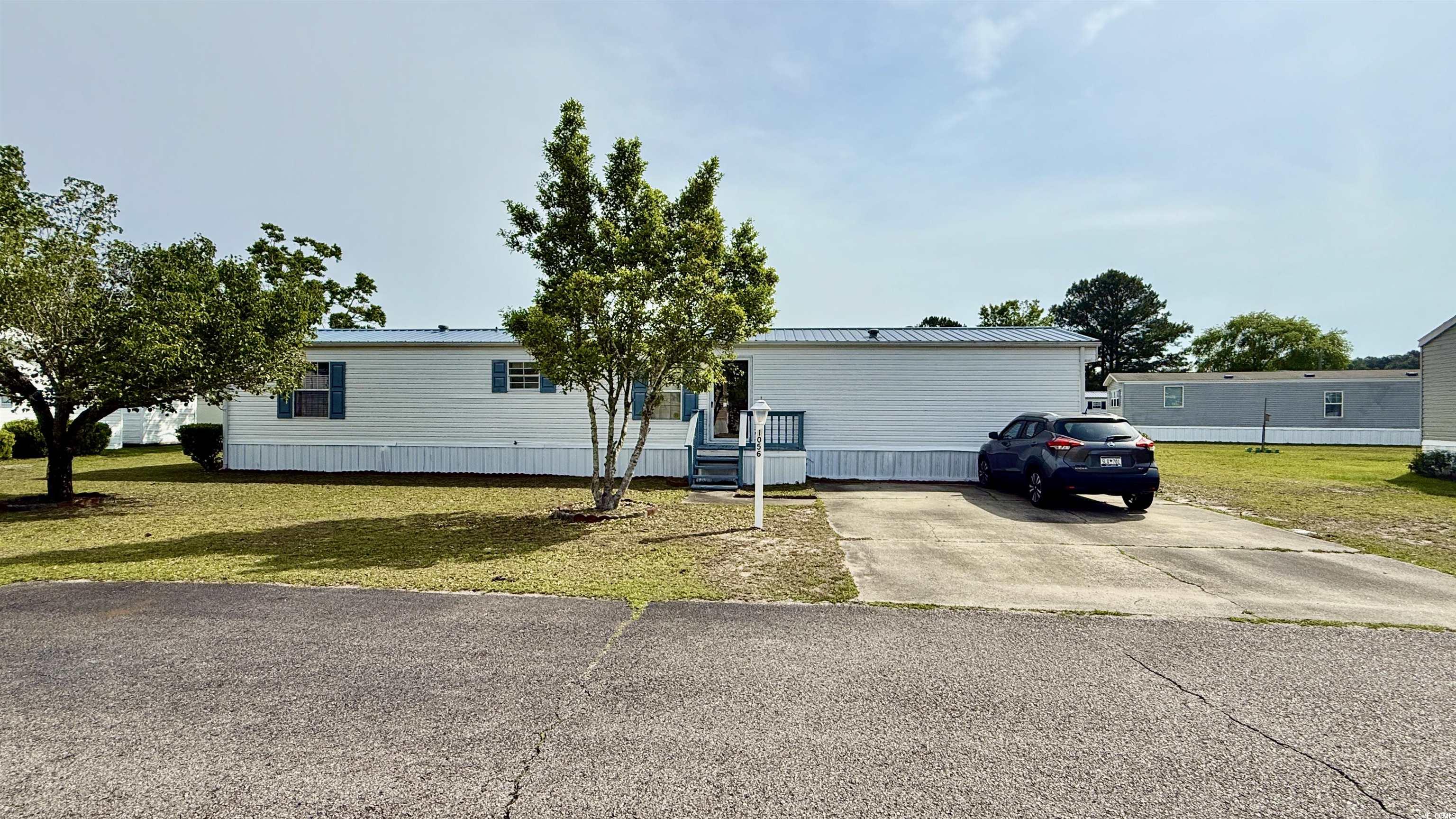 Manufactured / mobile home featuring a front yard, metal roof, and concrete driveway