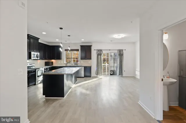 a view of kitchen with stainless steel appliances kitchen island wooden cabinets and granite counter tops
