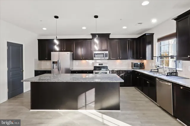 a large kitchen with stainless steel appliances kitchen island granite countertop a sink a stove and refrigerator