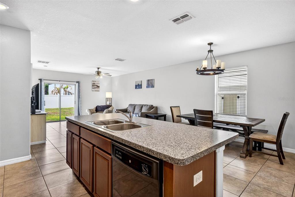 9616 Lemon Drop Loop Sun City Center, FL 33573 - Photo 13 of 53 a kitchen with a stove a sink a kitchen island with wooden cabinets and floor
