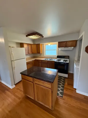 a kitchen with granite countertop a refrigerator and a stove top oven