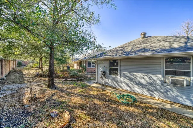 a view of a house with a yard and large tree