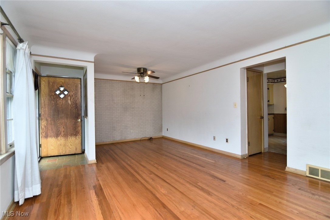 9421 David Road Cleveland, OH 44125 - Photo 6 of 36 Spare room with ceiling fan, light wood-style floors, and brick wall