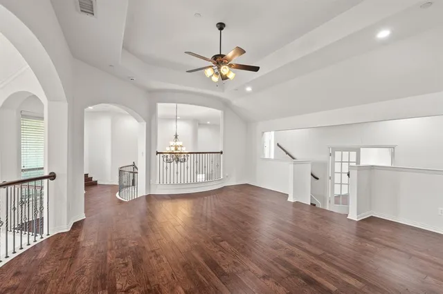 a view of a livingroom with wooden floor a ceiling fan and windows