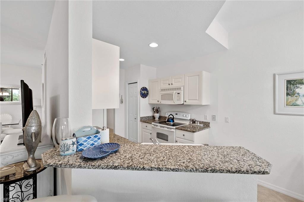 4685 Hawks Nest Way, Unit 103 Naples, FL 34114 - Photo 12 of 35 a kitchen with stainless steel appliances granite countertop a sink stove and refrigerator