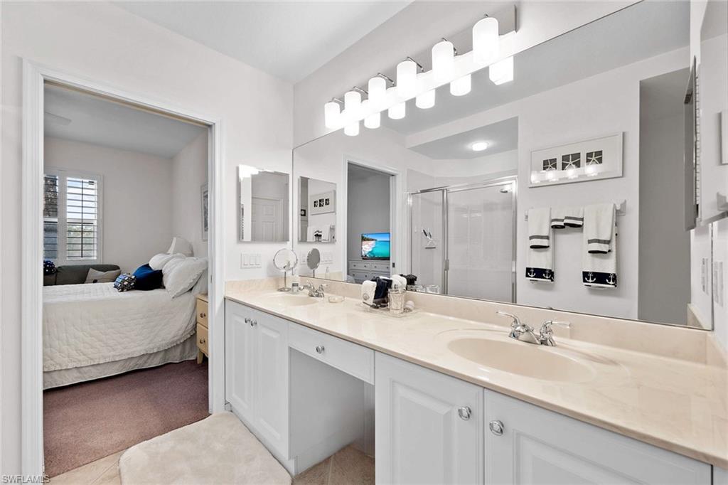 4685 Hawks Nest Way, Unit 103 Naples, FL 34114 - Photo 17 of 35 a en suite bathroom with a double vanity sink mirror and chandelier