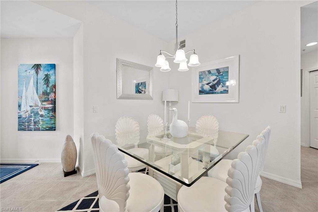 4685 Hawks Nest Way, Unit 103 Naples, FL 34114 - Photo 18 of 35 a view of a dining room with furniture a chandelier and wooden floor