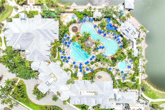 a small pool with lawn chairs and large trees